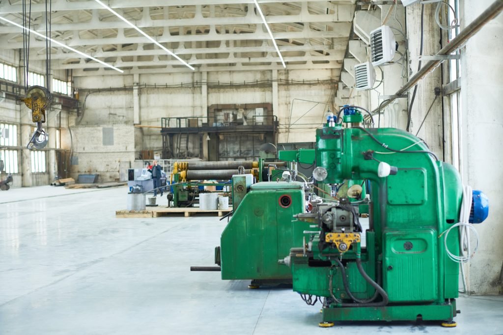 Green drilling machine and other industrial equipment in spacious shop illuminated with light