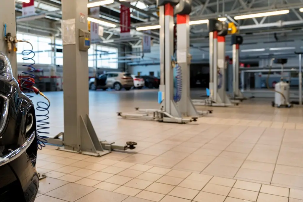 Close-up of black car in car service station, with soft-focus, lifts for raising and repearing and other cars in the background, selective focus